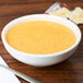 A Tuxton eggshell china bowl of soup on a table with crackers.