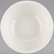 A white Tuxton nappie bowl with a white rim on a gray surface.