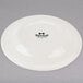 A Tuxton Reno ivory china plate with black text reading "Tuxton" in cursive.