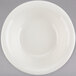 A white Tuxton Reno china fruit bowl with a white rim on a gray background.