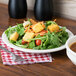 A Tuxton Nevada ivory china plate with a salad with croutons, tomatoes, and vegetables.