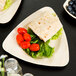 A TreeVive triangular palm leaf plate with a tortilla and vegetables.