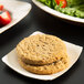 A TreeVive by EcoChoice square palm leaf plate with two cookies, salad, and fruit on a table.