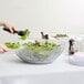 A woman using a Carlisle Petal Mist bowl to cut salad.