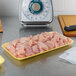 A yellow CKF foam meat tray on a counter filled with raw chicken meat.