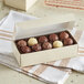 A 1 lb. gold linen candy box on a towel with a box of chocolates inside.