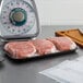 A black foam meat tray with raw meat on it on a counter.