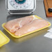 A yellow foam CKF meat tray with two raw chicken breasts on a counter.