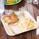A TreeVive palm leaf plate with a sandwich on it on a table.