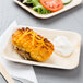 A TreeVive rectangular palm leaf plate with a salad and a potato on it on a table.