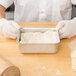 A person in gloves using an American Metalcraft aluminum cake pan to hold dough.