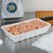 A white CKF foam meat tray holding raw chicken meat on a counter.