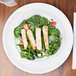 An Arcoroc brunch plate with a sandwich, strawberries, and spinach on a table.