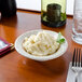 A Tuxton eggshell china bowl filled with mashed potatoes on a table.