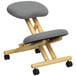 A Flash Furniture wooden kneeling office chair with wheels and a grey seat.