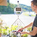 A man weighing fruit on a Cardinal Detecto solar power hanging scale.