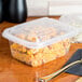 A Genpak clear plastic rectangular lid on a plastic container with food in it.