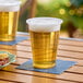 A translucent plastic cup of beer on a table in a brewery tasting room.