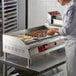 A man in a white shirt cooking eggs on an Avantco electric countertop griddle.