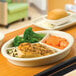 A Hall China divided plate with food including broccoli and carrots on a table.