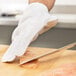 A person wearing a Victorinox cut resistant glove cutting meat on a cutting board.