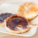 A bagel with Musselman's Apple Butter spread on it on a plate.