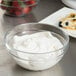 Arcoroc glass bowl filled with whipped cream next to a bowl of strawberries.