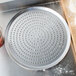 An American Metalcraft Super Perforated Heavy Weight Aluminum Pizza Pan with a metal tray on it with holes.