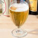 A Libbey Teardrop goblet filled with beer on a table.