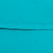 A close-up of a teal fabric with a hemmed edge.