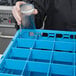 A person using a Carlisle glass rack to hold clear glass containers.