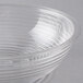 A clear Camwear round ribbed bowl on a gray surface.