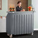 A woman standing behind a Cambro portable bar with drinks.