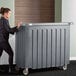 A woman pushing a Cambro granite gray and slate gray portable bar.