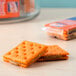 Two Lance Toast Chee crackers with peanut butter filling on a table next to a box of Lance Toast Chee crackers.