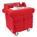 A red plastic Cambro CamKiosk portable hand sink with two sinks and faucets on a red counter.