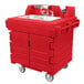 A red plastic Cambro CamKiosk portable hand sink with double sinks on wheels.