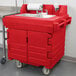 A red plastic Cambro CamKiosk portable hand sink with wheels.