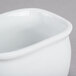 A white porcelain sugar packet holder with a lid on a white surface.