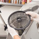 A person in gloves holding a circular Hobart Dicing Grid over a counter.