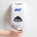 A person using a Purell TFX foaming hand sanitizer dispenser.