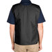 The back view of a person wearing a black Intedge cobbler apron over a vest.