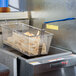 A Pitco twin fryer basket with food in a fryer.