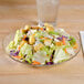 An Arcoroc Fleur glass dinner plate with a salad and a glass of water.