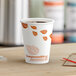 A close-up of an EcoChoice Leaf Print paper hot cup filled with coffee on a table.