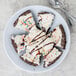 A white melamine bowl with a piece of cake with white frosting and sprinkles on a plate.