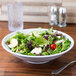 A white melamine bowl with a salad containing eggs and tomatoes.