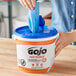 A person removing a GOJO Fast Towel from a bucket.