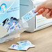 A hand putting a packet of Purell Cottony Soft Sanitizing Wipes into a dispenser.