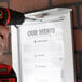 A hand using a screwdriver to fix an Aarco Snap Frame to a menu.